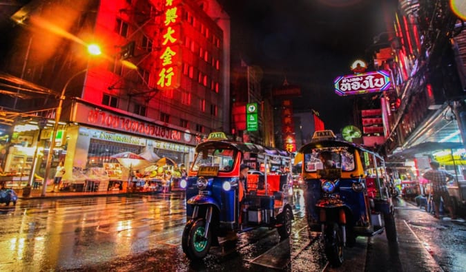 An up-close shot of the tuk-tuks in Bangkok, surrounded by bright neon lights at night