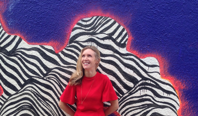 Best selling author Helen Russell posing in front of a colorful mural