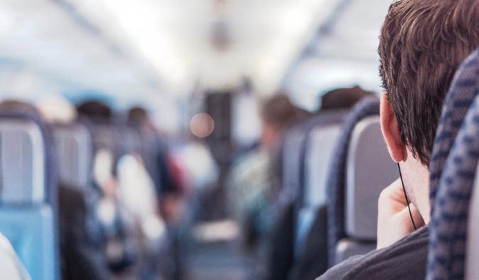 A man sitting alone on a busy airplane mid flight