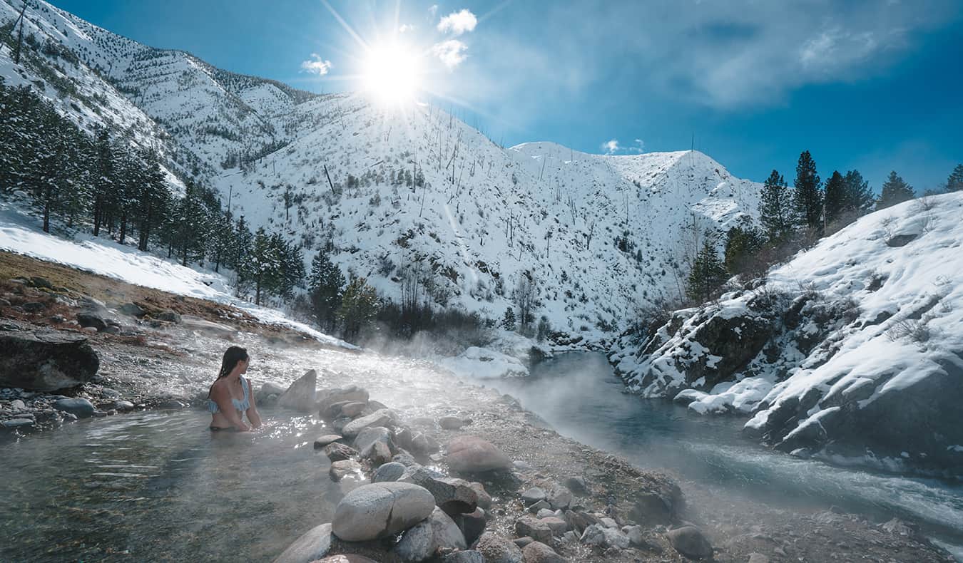 Kristin Addis sitting in hot springs in the snow-capped mountains