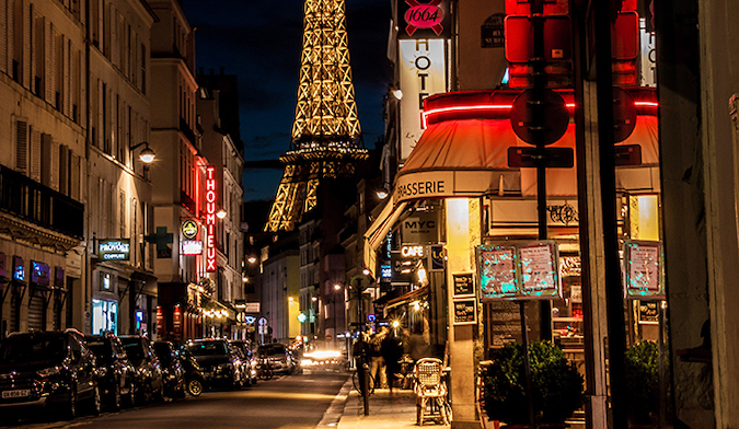 people walking in front of the Eiffel Tower at night