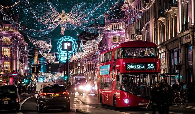 a red London bus with Christmas lights at night