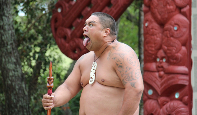 A large Maori warrior holding a spear while performing in New Zealand