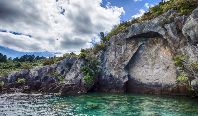 A Maori mural carved into stone near the water in New Zealand