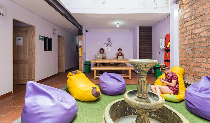 Common area with purple and yellow bean bags and people working on laptops at Purple Monkey, Medellin