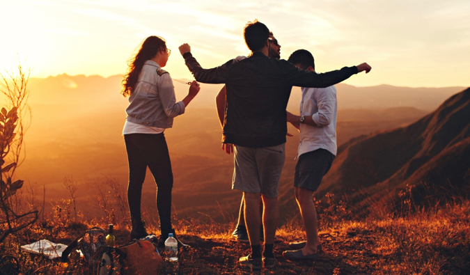 A group of travelers having a picnic on a mountain at sunset