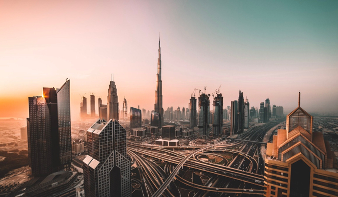 The massive Burj Khalifa and surrounding skyscrapers and roads in Dubai at sunrise