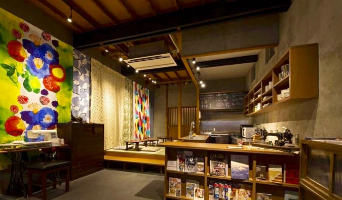Common room with front desk, bookshelves, and seating in traditional Japanese design at the Sheena and Ippei hostel in Tokyo, Japan