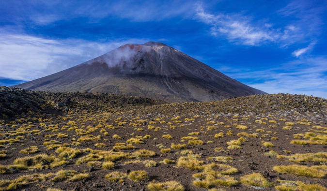 A blue sky above the dark, steep slopes of Mount Ngauruhoe in the Tongariro Alpine Crossing in New Zealand