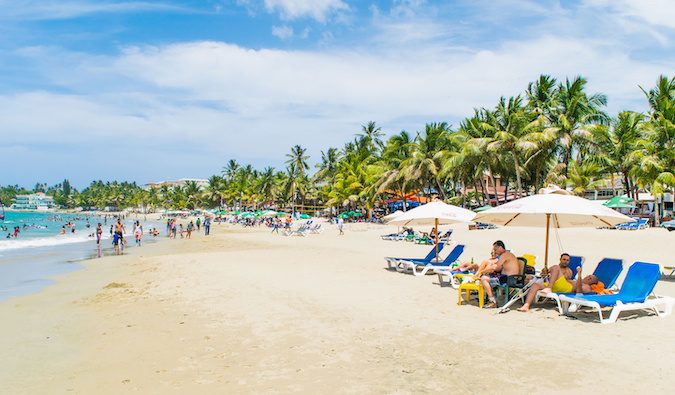 people lounging in beach chairs on a crowded beach