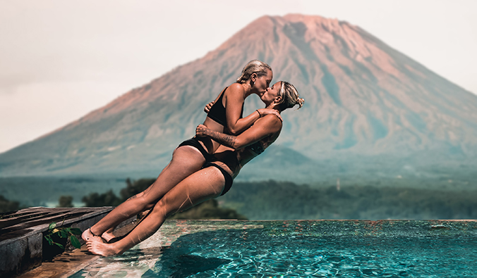 Charlotte and Natalie diving into a pool in front of a volcano in Bali