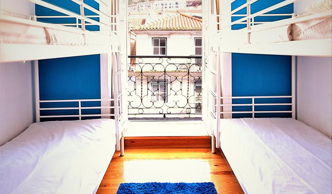 White bunk beds on either side of window looking out onto rooftops of Lisbon at We Love F. Tourists, Lisbon