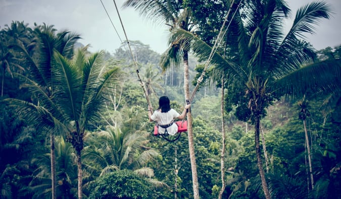 A solo female traveler on a swing in Bali in the jungle