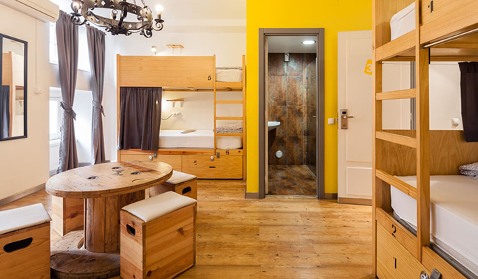 Dorm room with wooden bunk beds and small round table at Yes! Lisbon Hostel