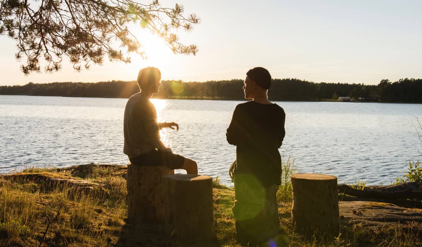 Two travelers having a conversation by a lake overseas