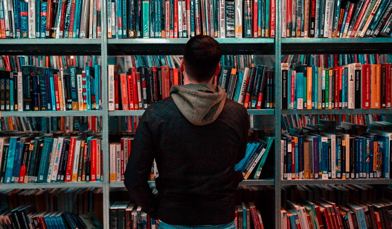 A man looking at a bookshelf in a library