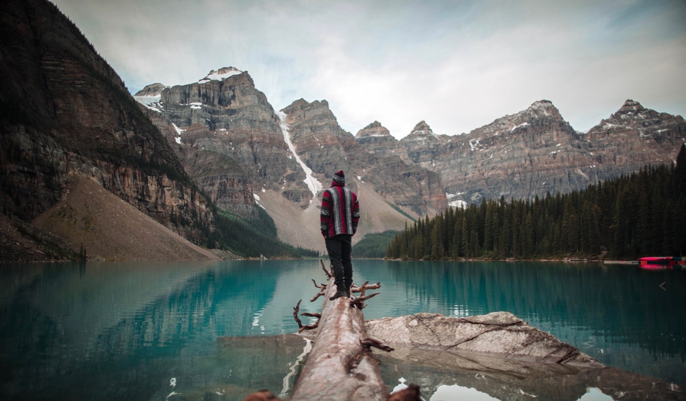 A solo traveler standing on a log in Alberta, Canada