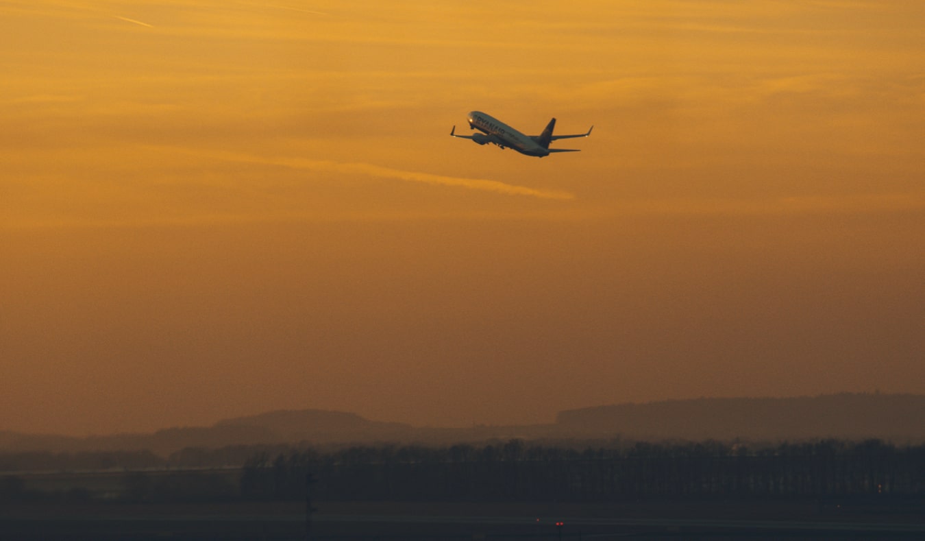 An airplane taking off during a unexceptionable orange sunset