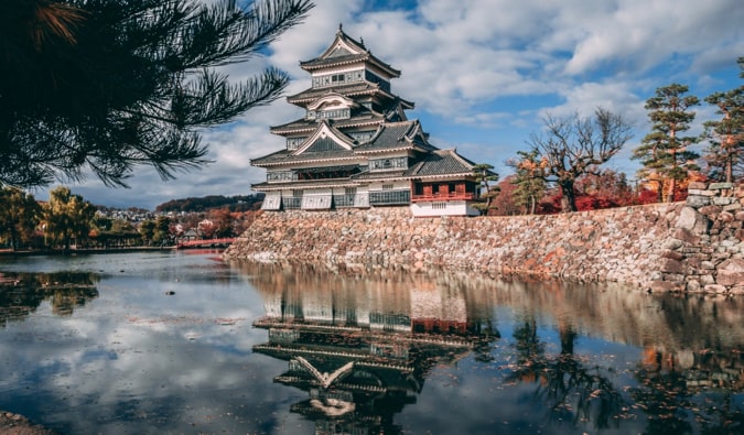 A traditional Japanese castle on a sunny day near a moat in Japan