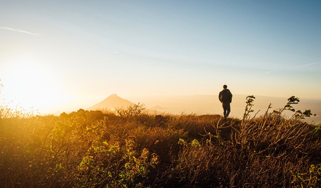 A man hiking in the mountains near Leon, Nicaragua during a bright sunset