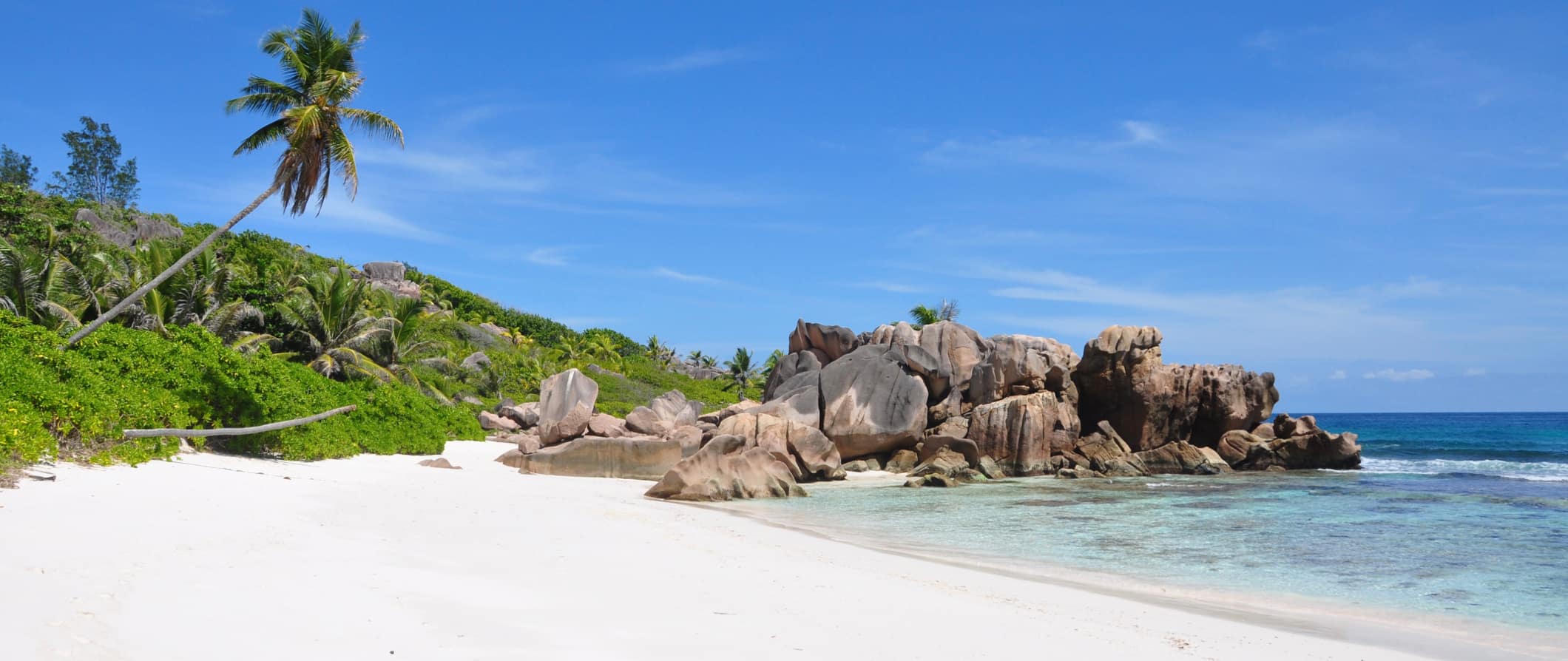 A tropical beach in Seychelles with white sand and a bright blue sky above