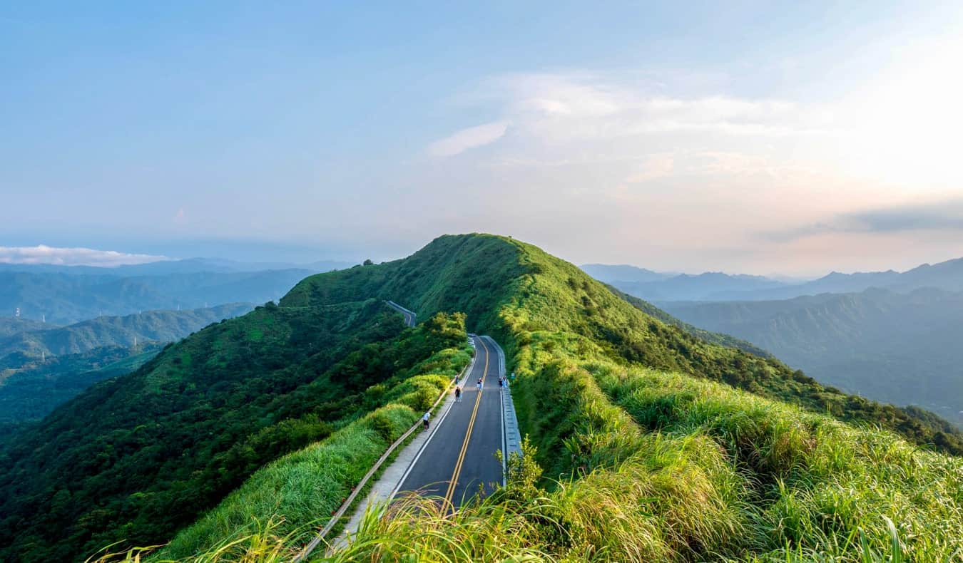 Hilltop view of a road disappearing around the top of the mountain