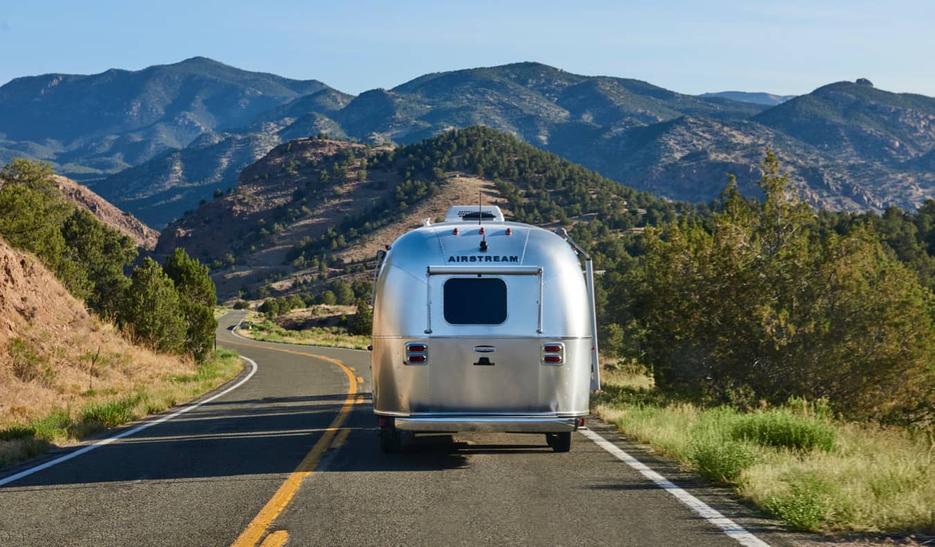 A vintage Airstream motorhome drives down an open road in the US.