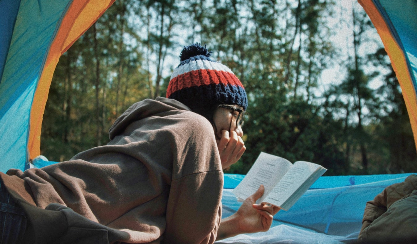 A traveler reading a book while inside a tent