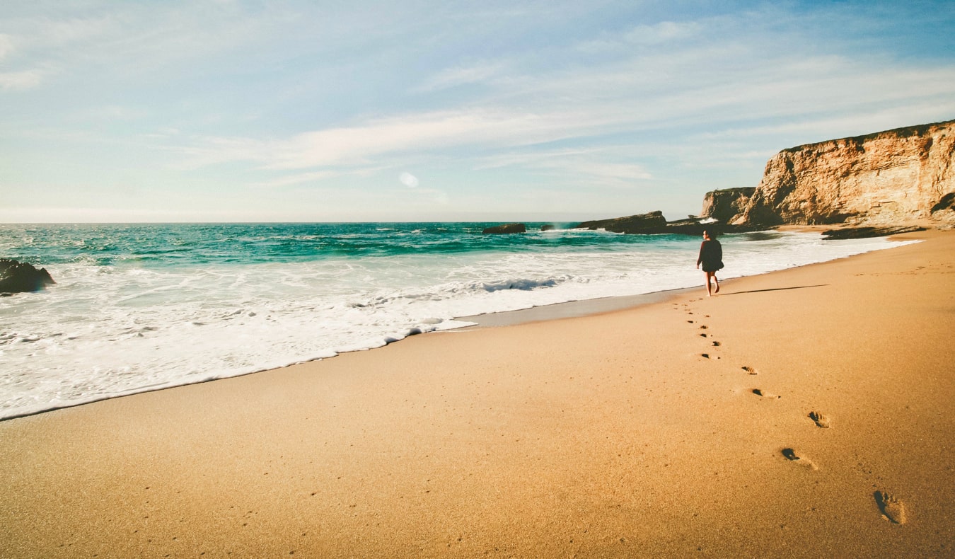 A solo female traveler walking alone on a beach