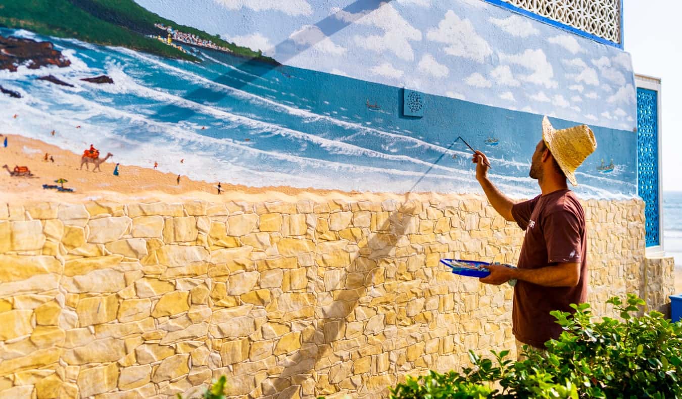 一个独自旅行的男性旅行者在户外的墙上画着彩色的壁画