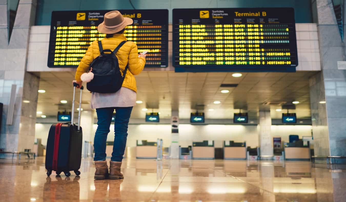 femme debout devant le tableau des départs à l'aéroport de Barcelone