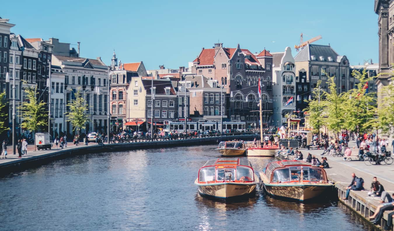 A narrow canal with boats in Amsterdam on a sunny summer day