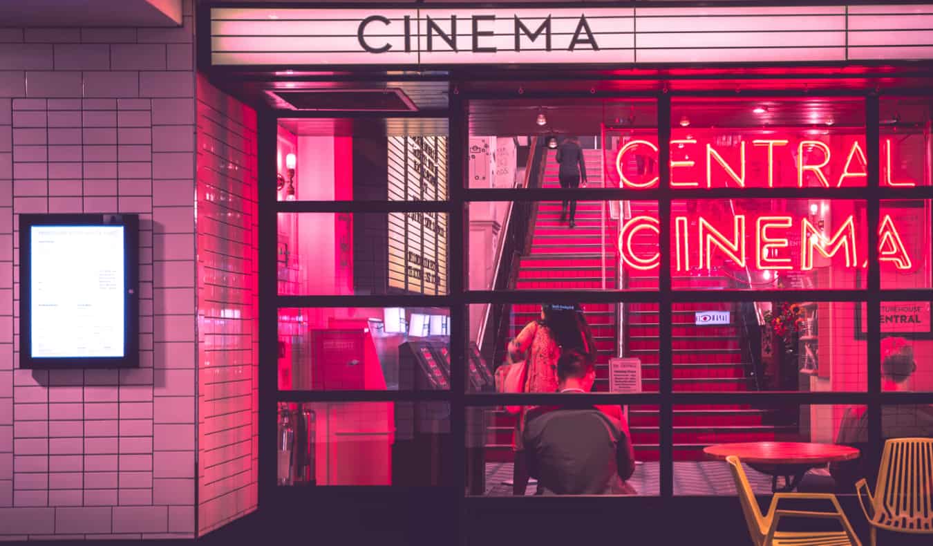 A cinema lit up at night with pink neon light