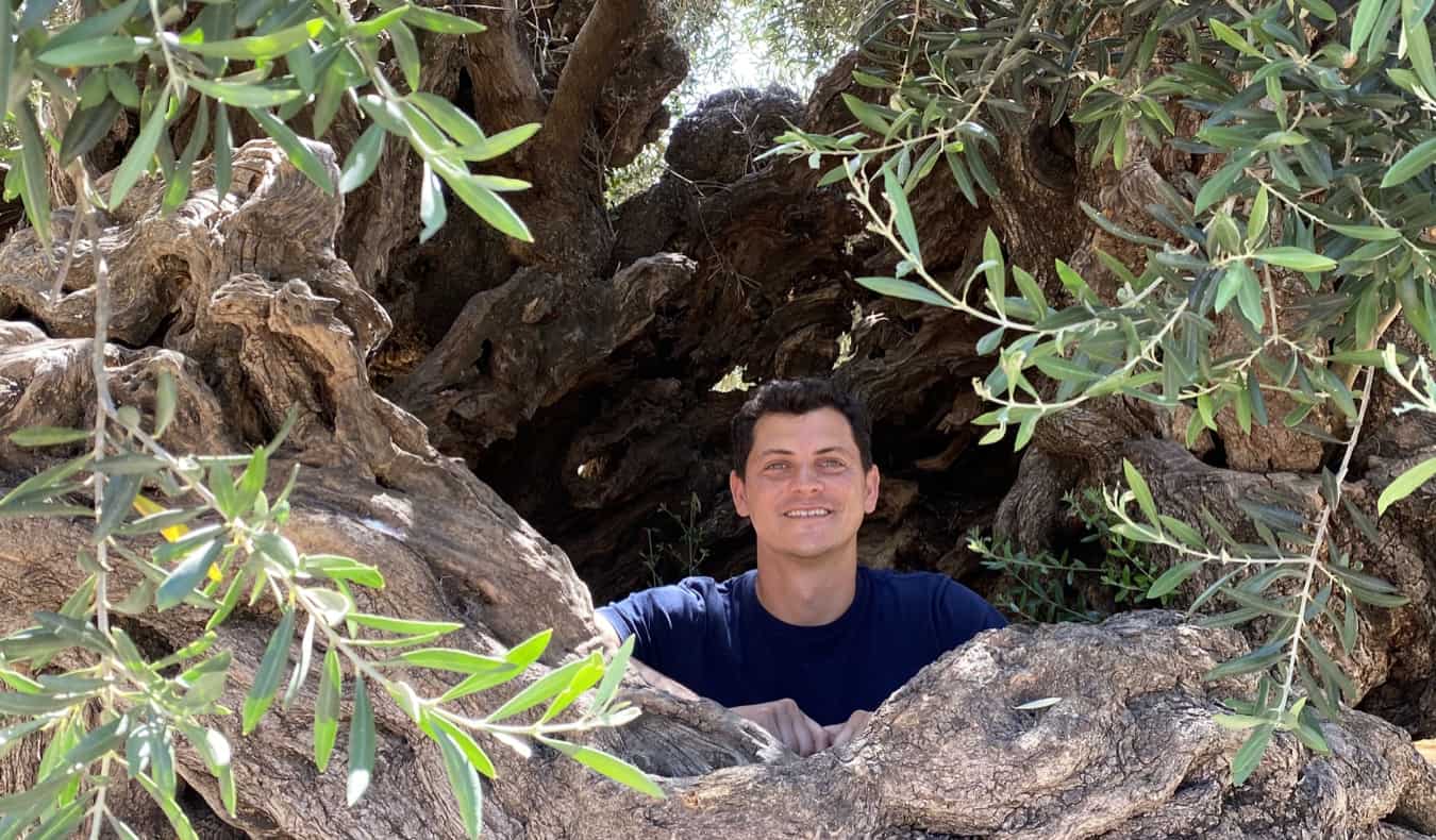 Nomadic Matt peeking through a hole in the rocks of Greece