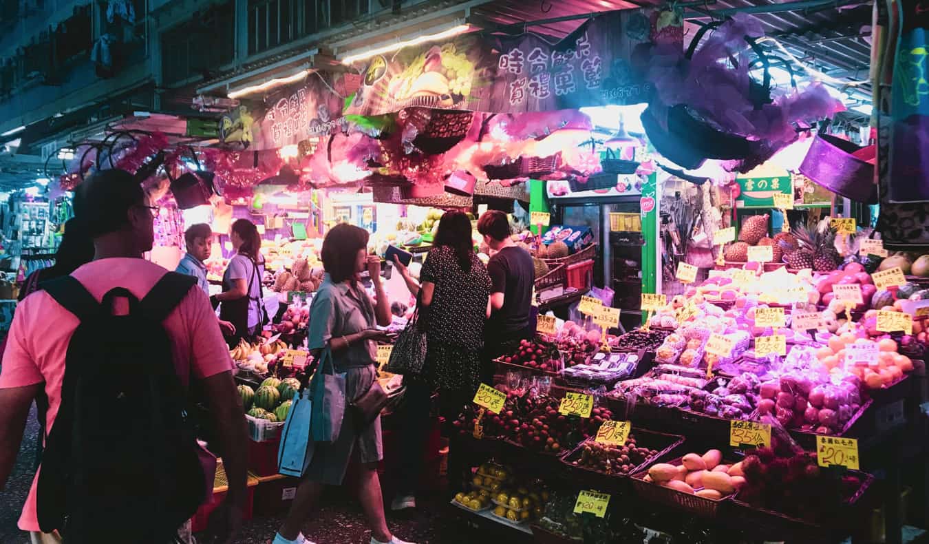 a small food market and the bustling streets of Hong Kong at night