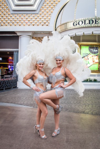 two women in sparkly costumes with white feather headdresses
