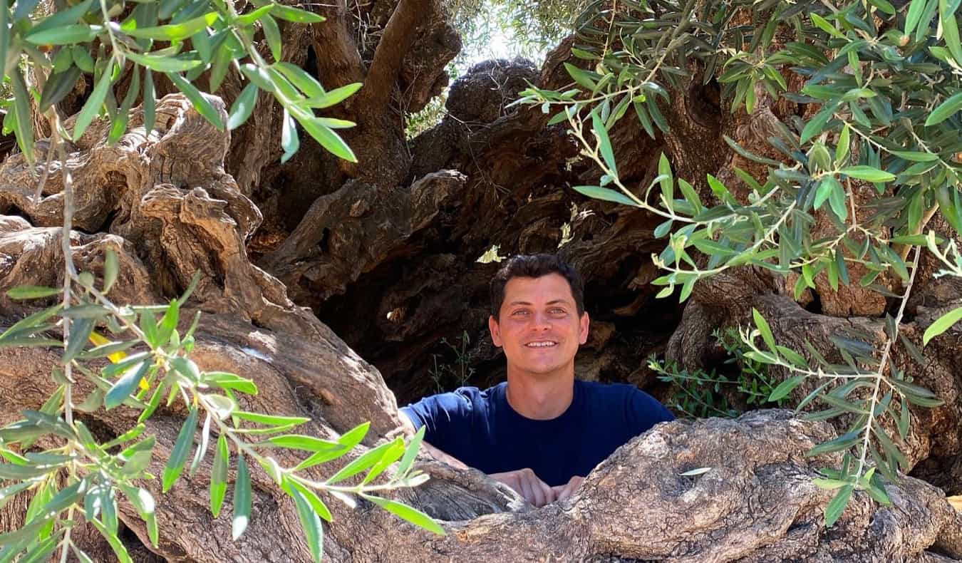 Nomadic Matt posing ina large hole in the forest while hiking in the Balkans