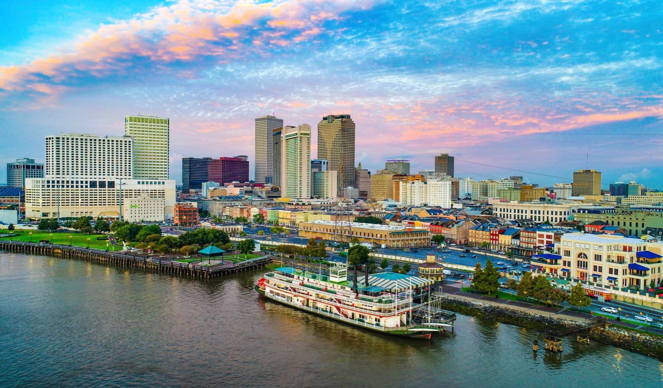 The skyline of New Orleans as seen from above the water, featuring an old steamboat