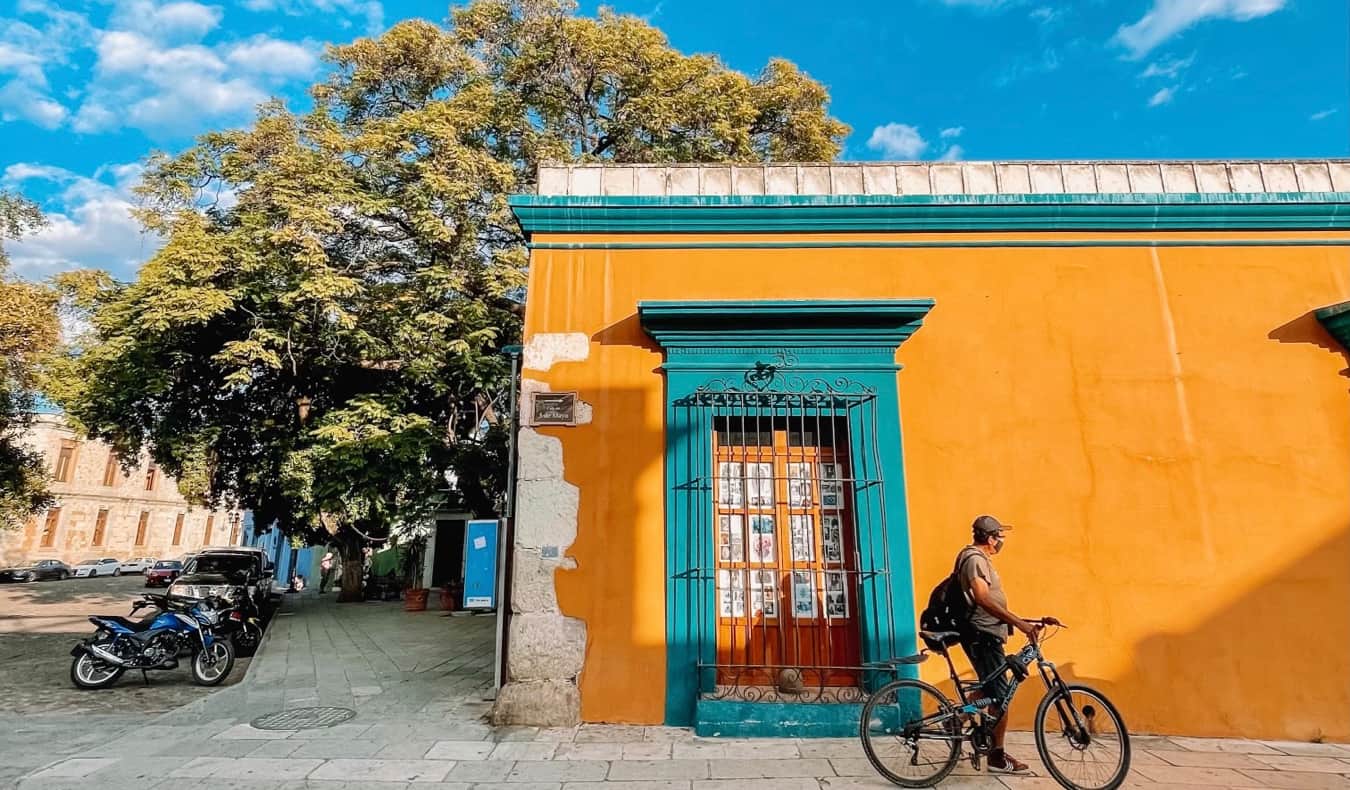 A local man in Oaxaca, Mexico with a bicycle near a colorful building