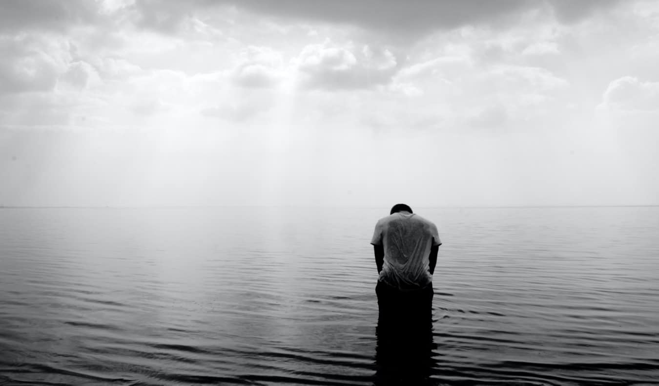 A black and white photo of a lone traveler alone in the water