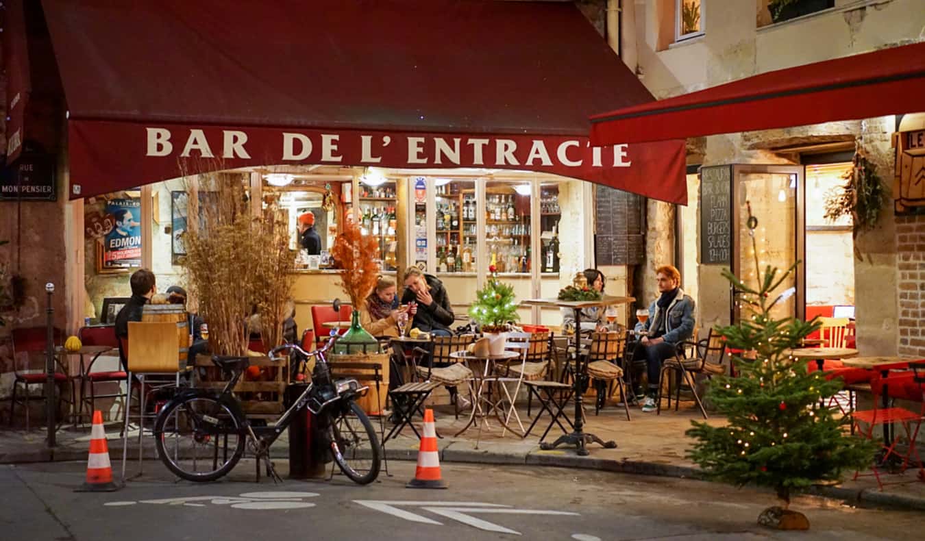 A cafe in Paris, France with people mingling outside on the sidewalk
