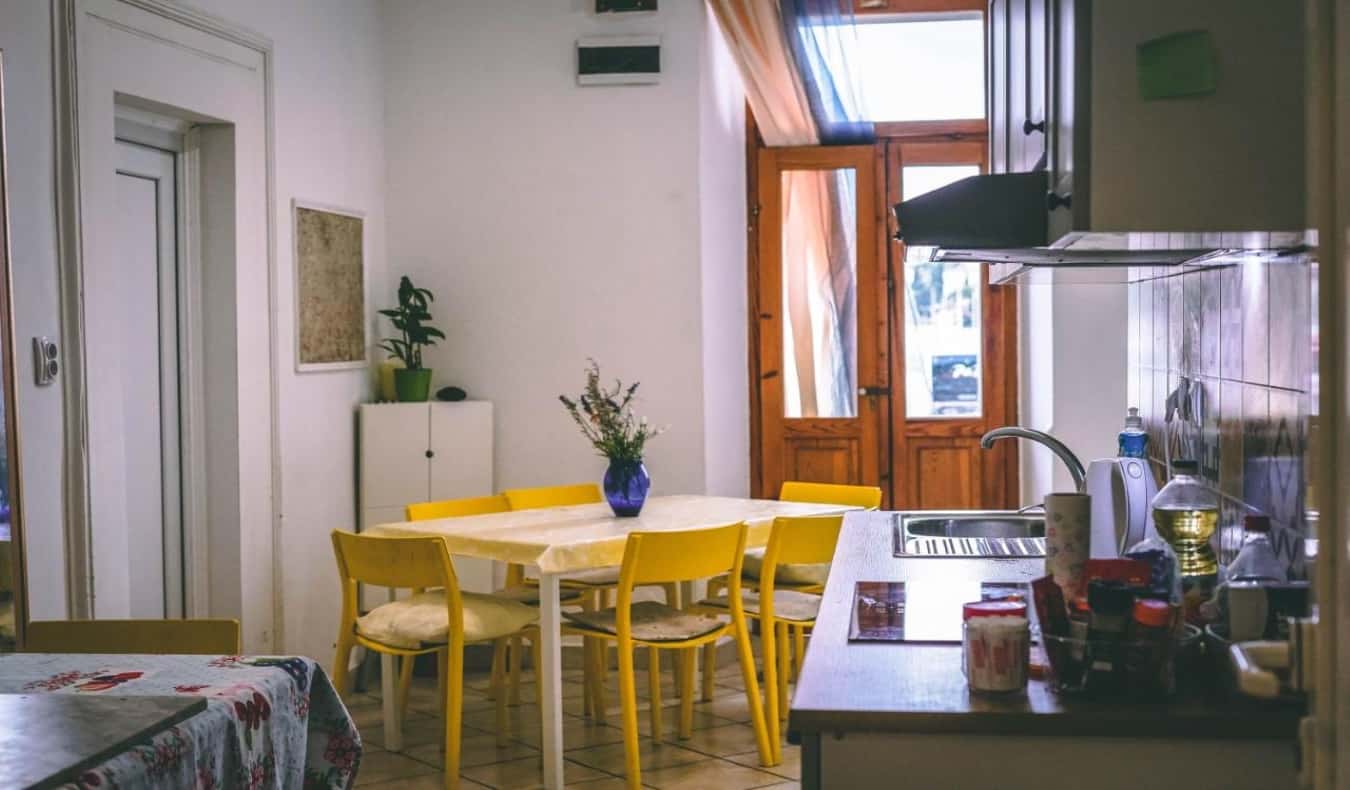 Homey kitchen area with a bright yellow table and wooden doors at Anchi's Guesthouse in Dubrovnik, Croatia
