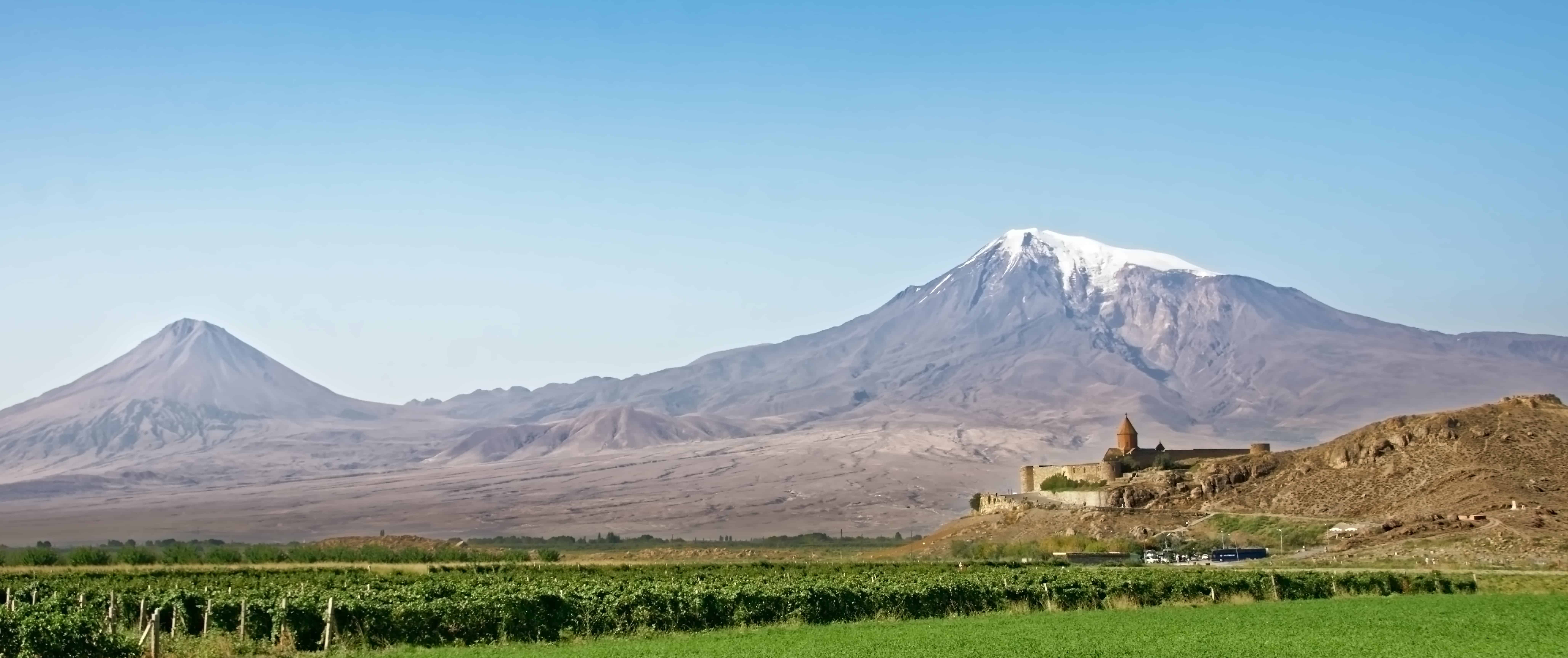 Sweeping landscape with vineyards, a monastery, and mountain in the background in Armenia