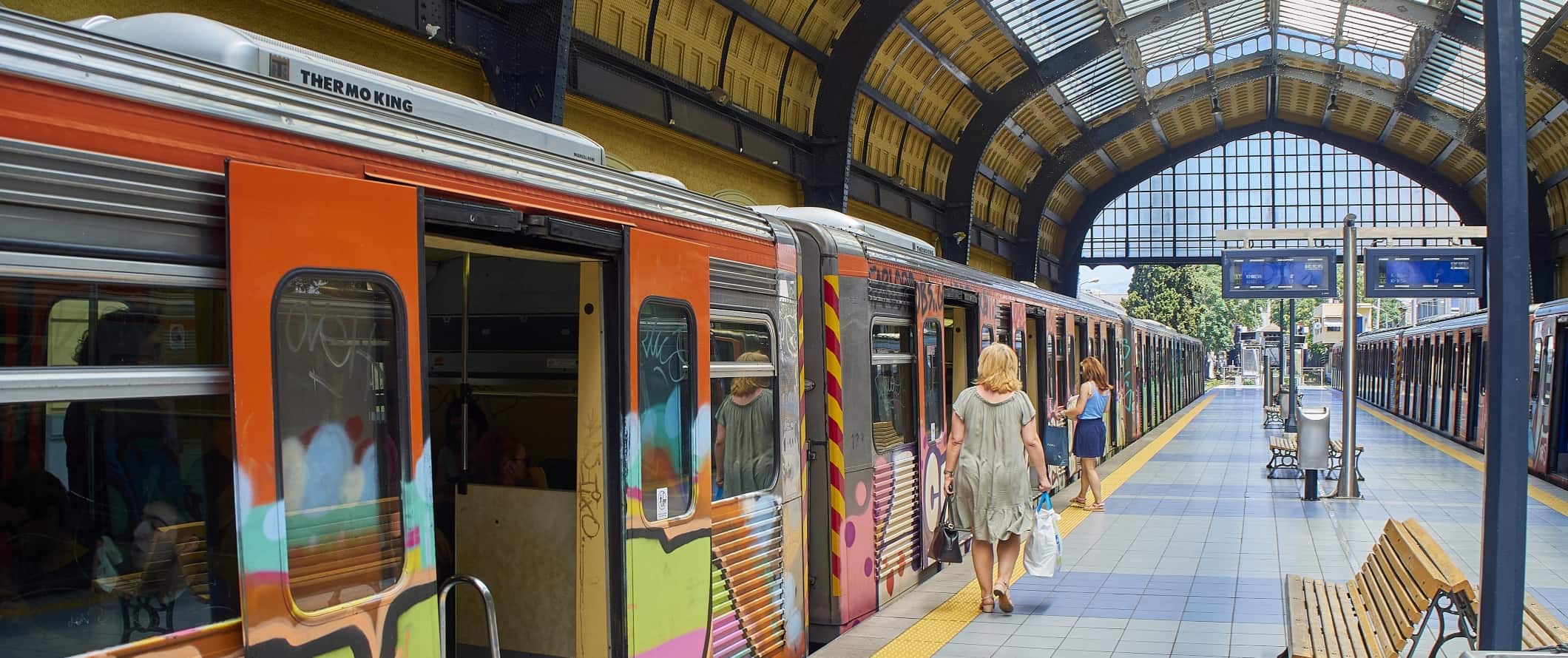 Bright, natural-light-filled train station in Athens with a colorful subway car.