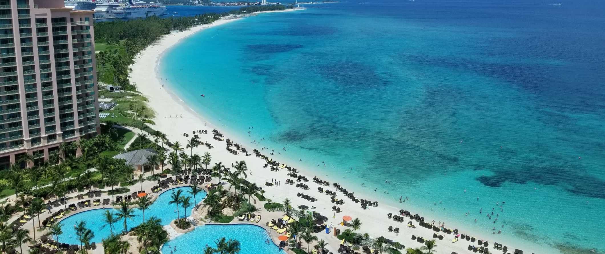 Drone view of resort pools at a large hotel along the beach with crystal clear turquoise waters in the Bahamas