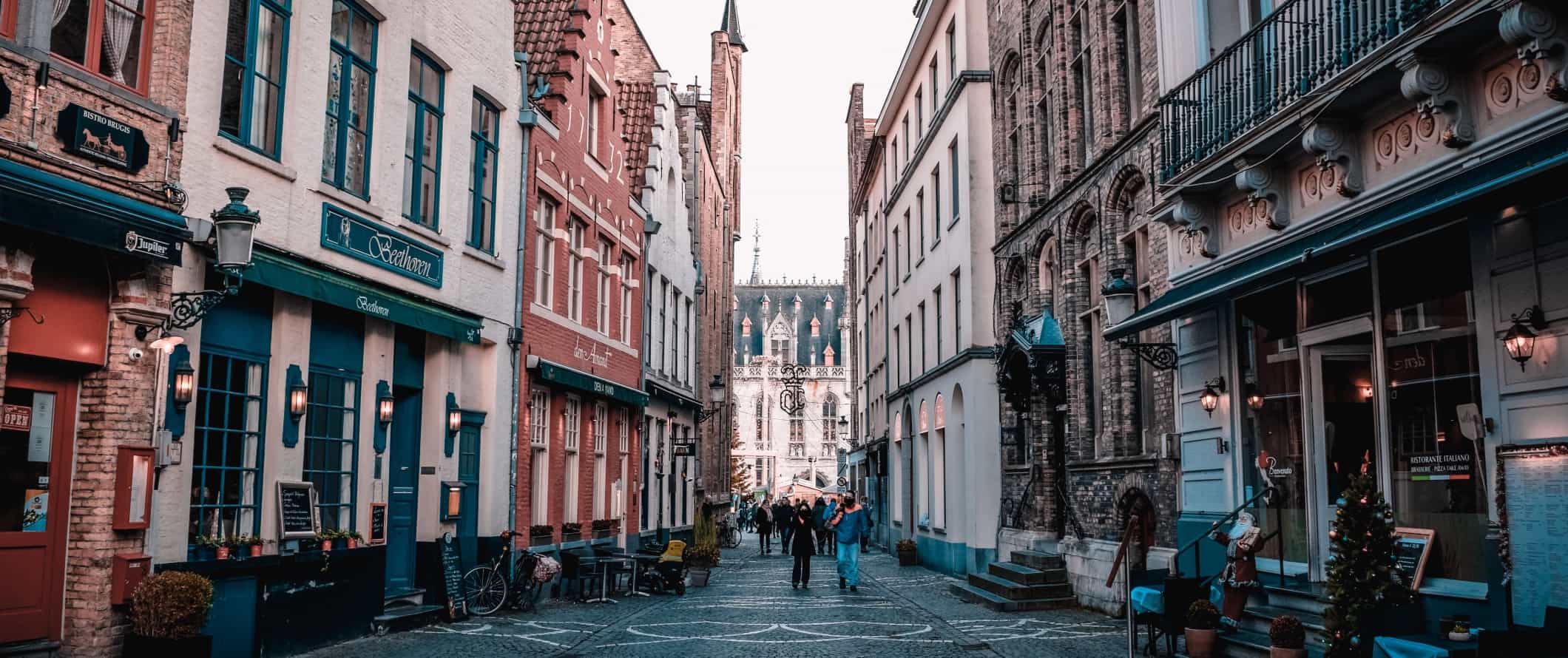 People walking down a pedestrianized cobblestone street in the historic center of Ghent, Belgium