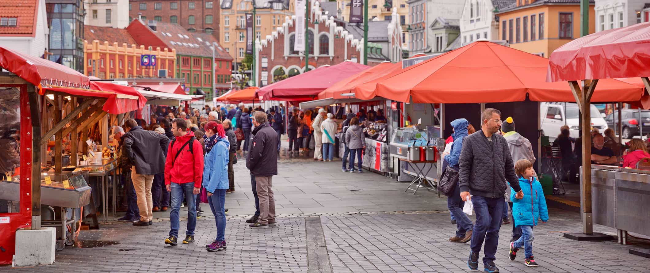 People exploring the bustling fish market on a sunny day in Bergen, Norway