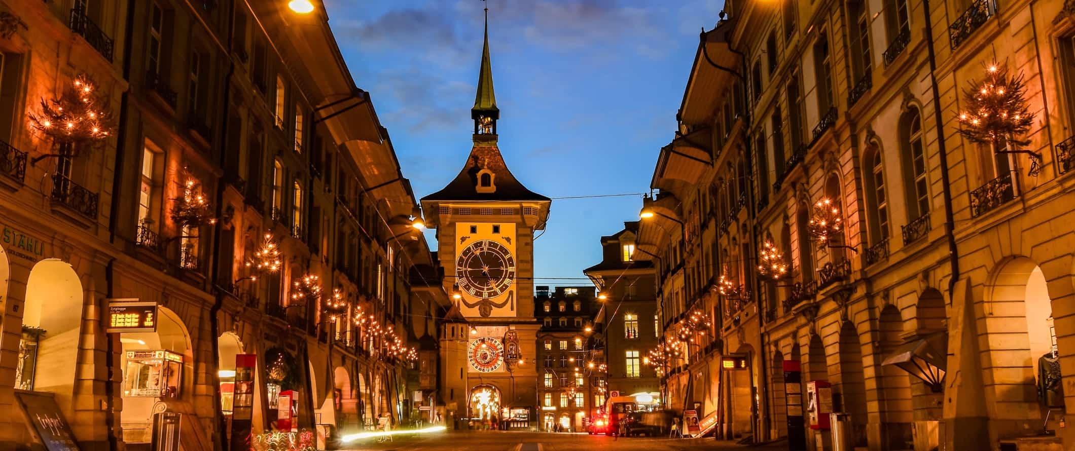 Expansive street with a historic clocktower at the end, lit up at night in Bern, Switzerland