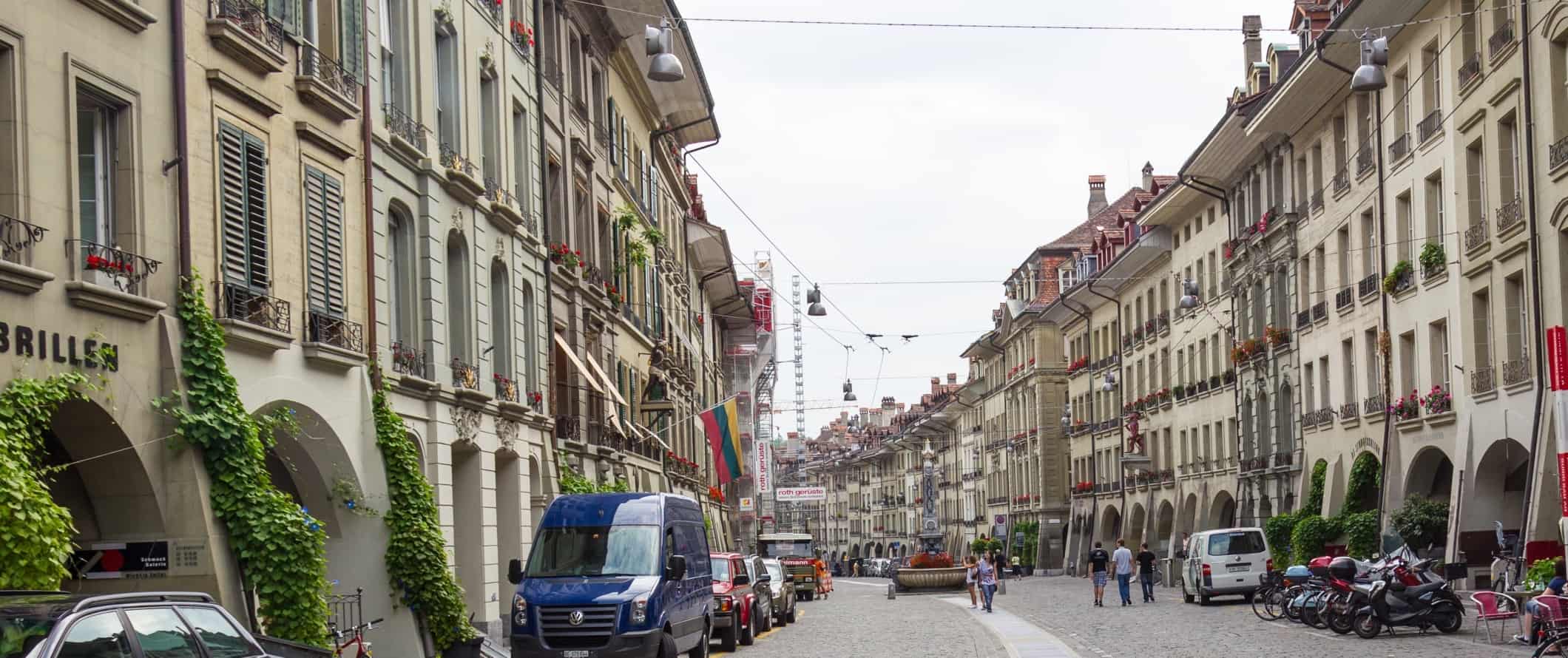 People walking down a cobblestone-lined street in the historic center of Bern, Switzerland