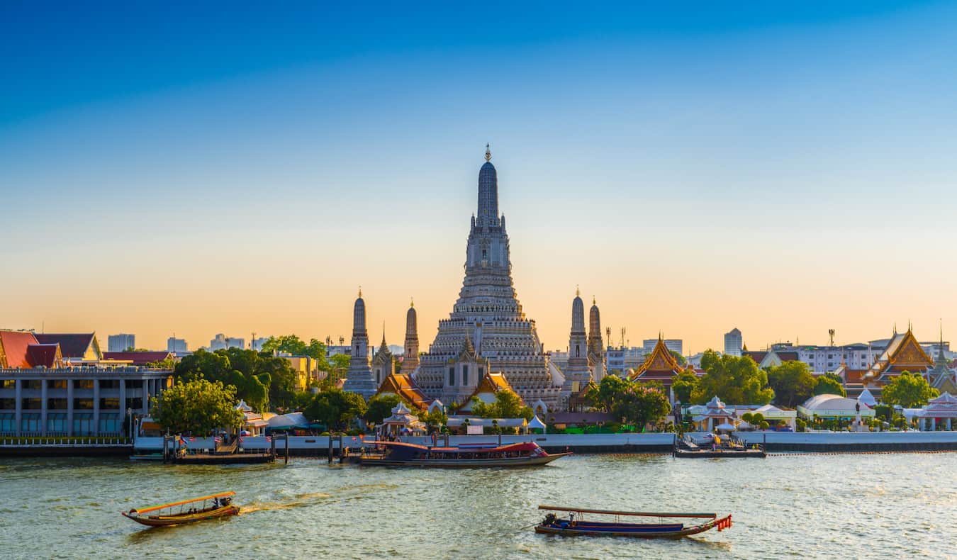 Cruise on the river in Bangkok, Thailand with a historic temple across the river in the background